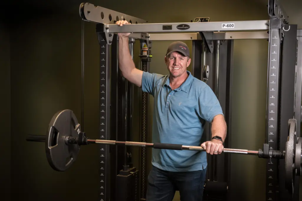 Man poses while using a weight machine.