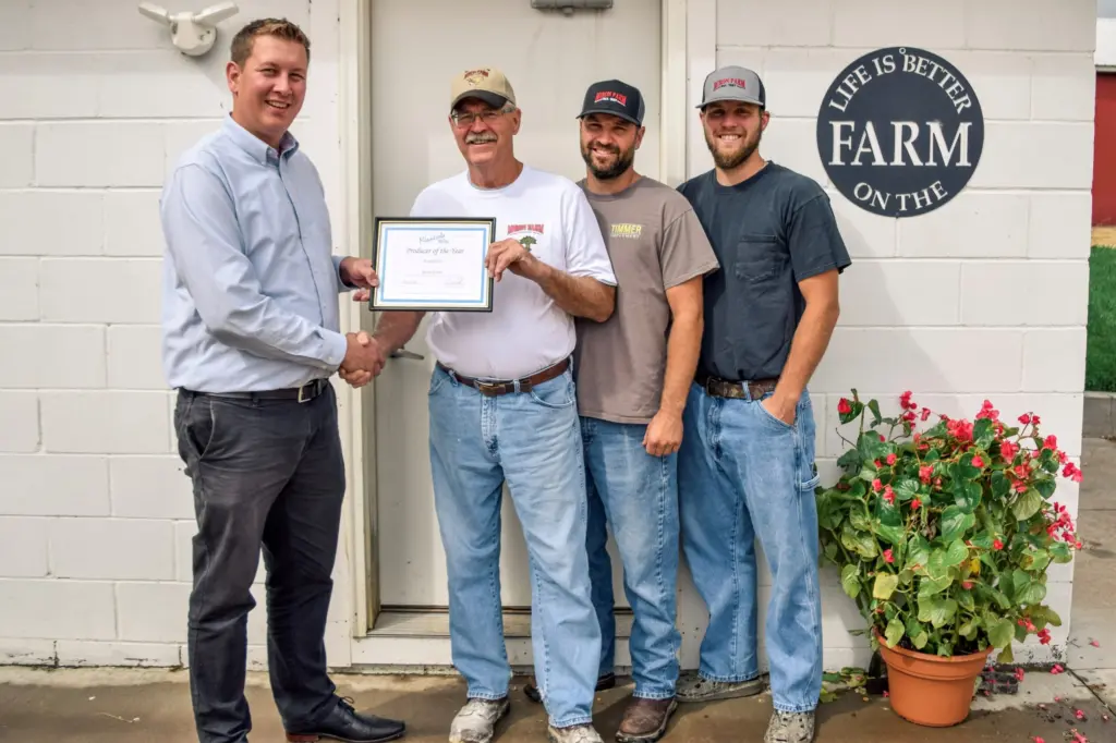 Four men pose with a plaque.