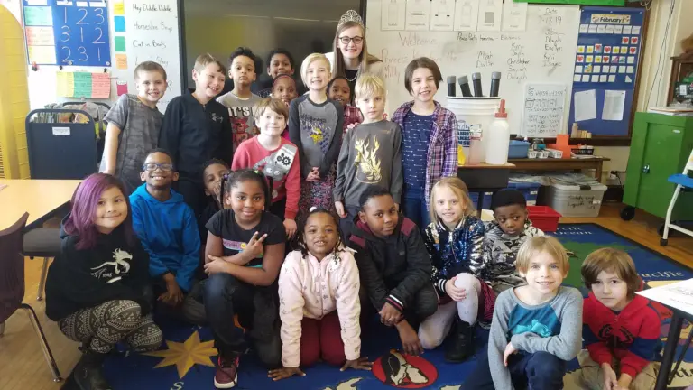 A group of students in a classroom pose with a dairy princess.