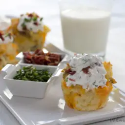 Baked potato cupcakes on a plate with garnishes, with a glass of milk.