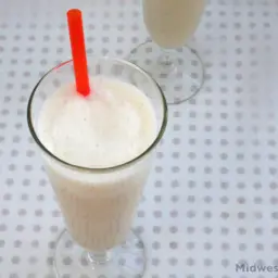 Banana caramel smoothie in a glass with a red straw.