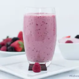 Chocolate berry smoothie next to a bowl of berries.