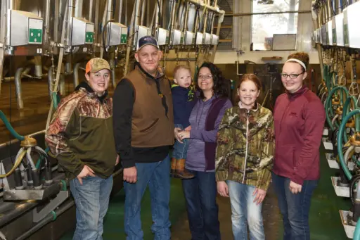 A farm family stands in their milking parlour.