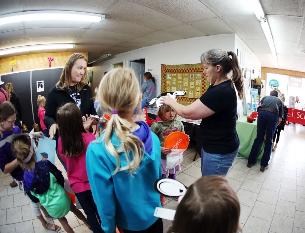 Adults put cow hats on children.