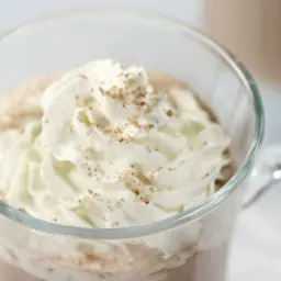 Hazelnut cafe au Lait in a glass with whipped cream.