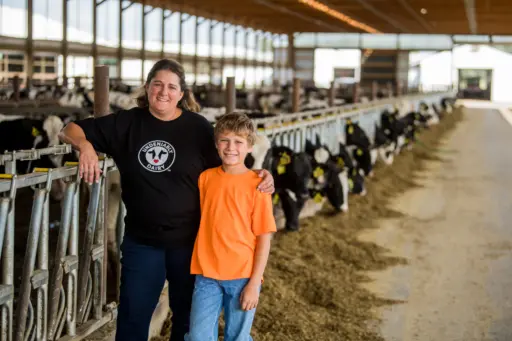 A lady and young boy stand in a barn.