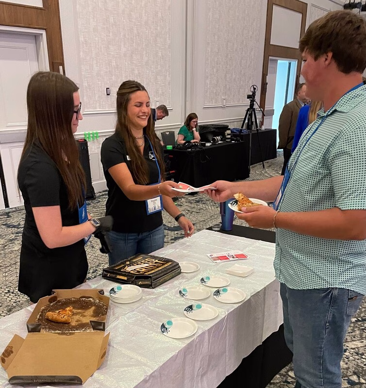 Ambassadors handing pizza to attendee