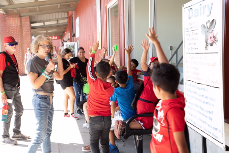 Students raising hands learning about dairy milking at Nebraska State Fair