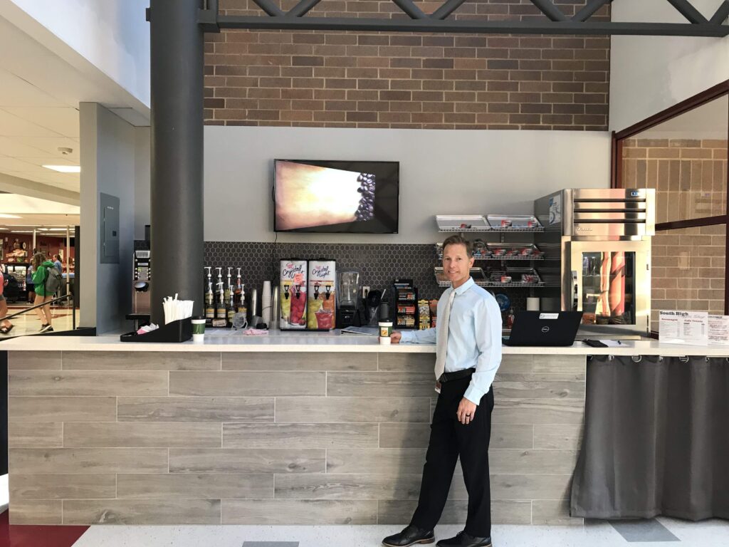 A man stands at the counter of a coffee bar.