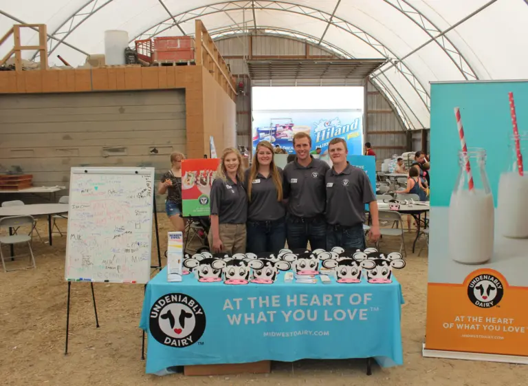 A group of teens stands at a table, next to an Undeniably Dairy display.