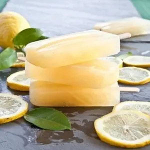 Lemon ginger ice pops on a table with mint leaves and lemon slices.