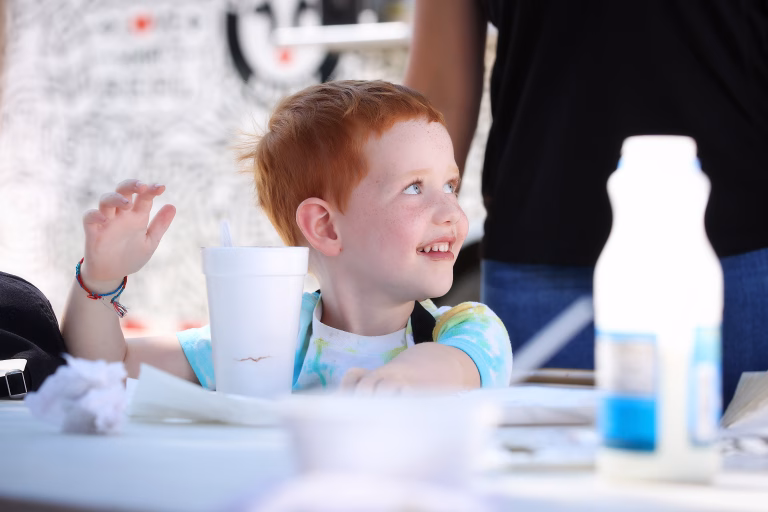 Little boy smiling, sitting with Styrofoam cup