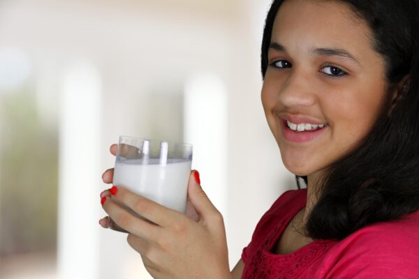 Teenage girl hold a glass of milk.