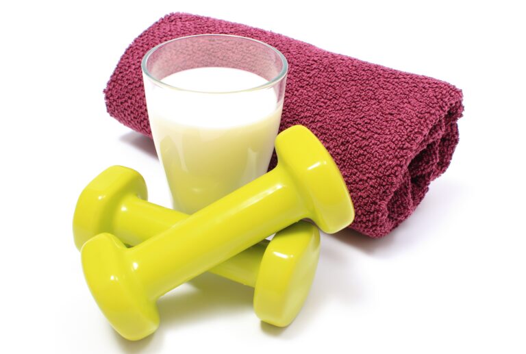 Green dumbbells, a purple fluffy towel, and a glass of milk, isolated on a white background.