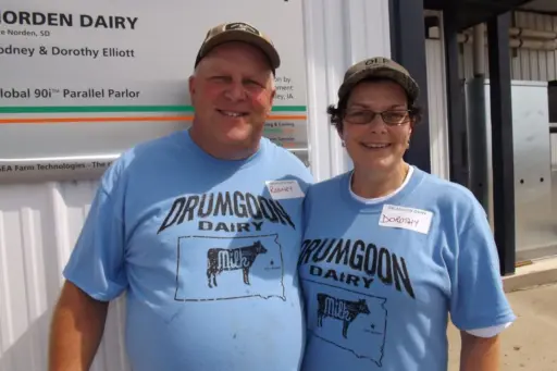 Rodney and Dorothy Elliott of Drumgoon Dairy in front of a metal building.