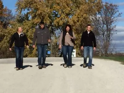 Four young people walk down a gravel road.