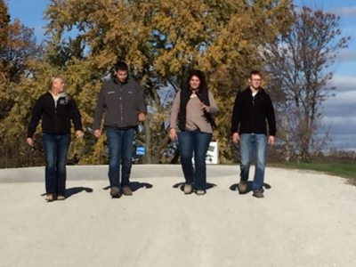 Four young people walk down a gravel road.