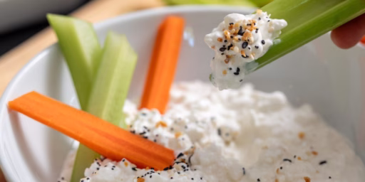 Close up of cottage cheese with seasoning, carrot sticks, and celery sticks