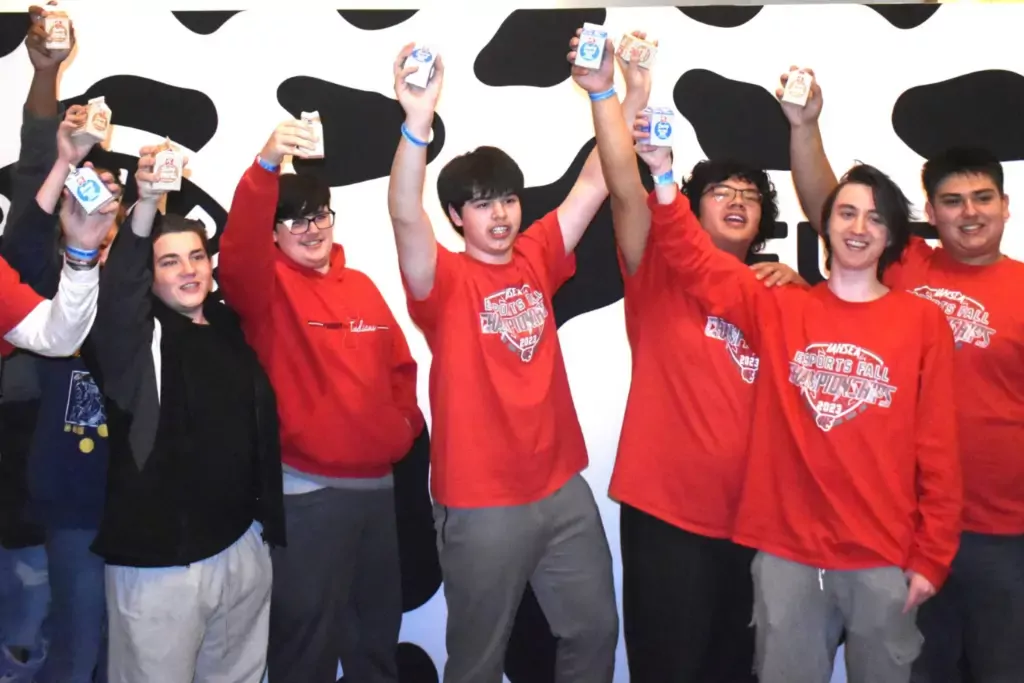 Students in red shirts holding up milk cartons