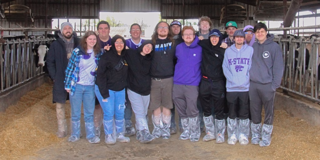 K-State gaming students standing in barn, smiling at camera