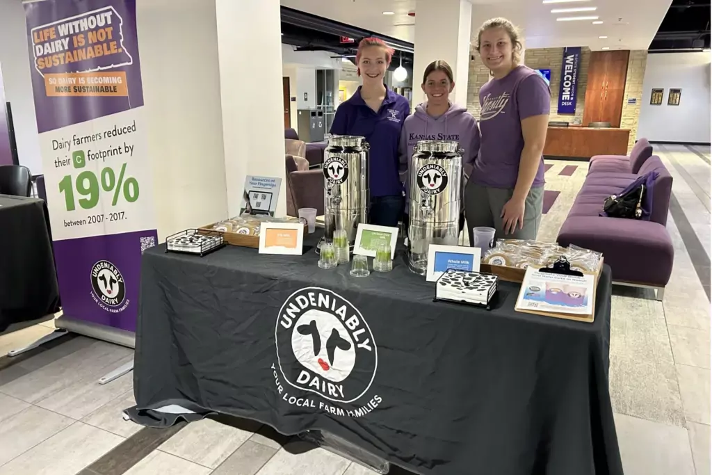 K-state students standing next to milk and cookies table