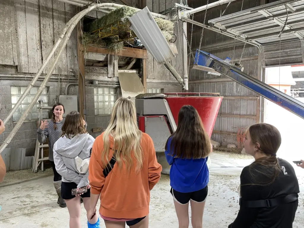 Students listening to dairy farmer in barn.