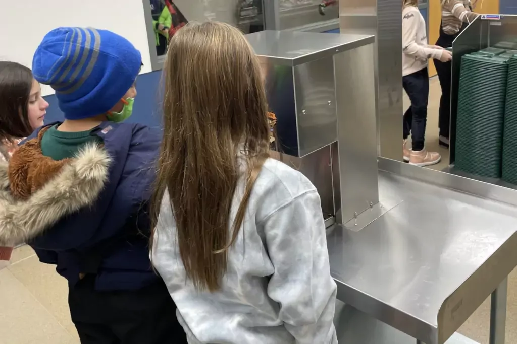 Students facing a bulk milk dispenser