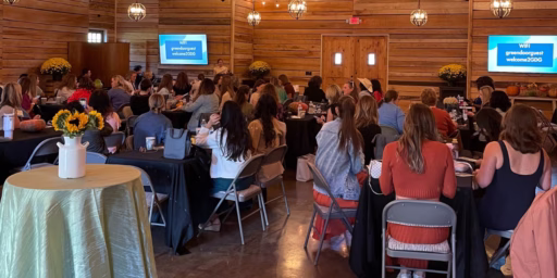 Group of people sitting at tables listening to a speaker