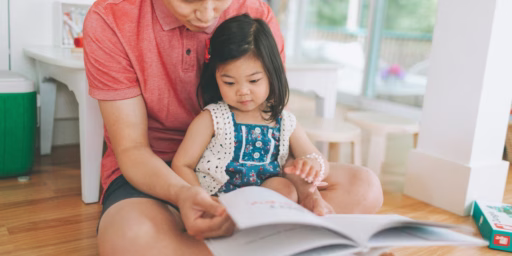 Child sitting in dad's lap reading book