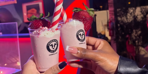 Hands holding up cups of dairy shakes at event