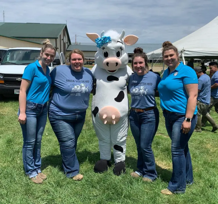 four young dairy women leaders with cow mascot